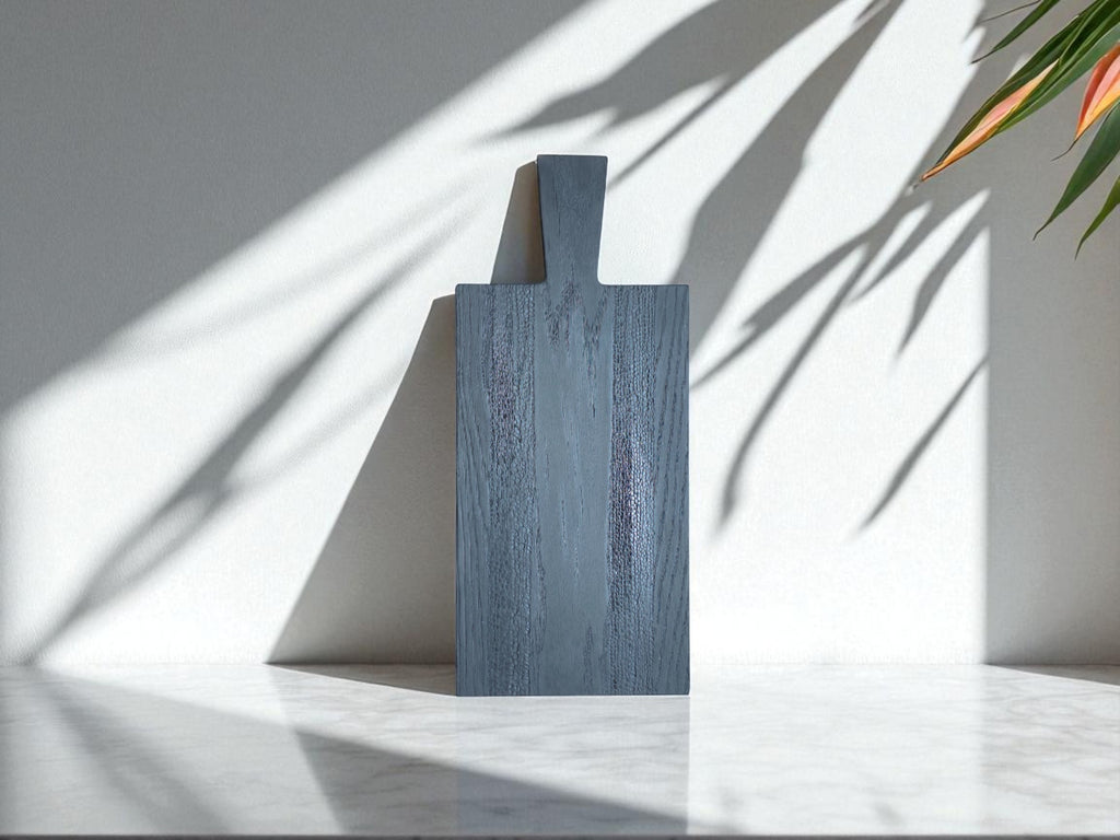 Entdecken Sie die ruhige Eleganz und die einzigartige Textur unseres Black Snake Boards. Dieses handgefertigte Brett aus massiver Eiche wird durch die traditionelle Yakisugi-Methode und unser BURN Painting veredelt. Das Spiel der Schatten an der Wand betont die natürliche Schönheit und die einzigartige Maserung des Holzes. Ein vielseitiges Stück für Ihre Küche und Ihr Zuhause.