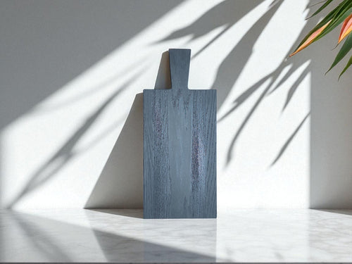 Entdecken Sie die ruhige Eleganz und die einzigartige Textur unseres Black Snake Boards. Dieses handgefertigte Brett aus massiver Eiche wird durch die traditionelle Yakisugi-Methode und unser BURN Painting veredelt. Das Spiel der Schatten an der Wand betont die natürliche Schönheit und die einzigartige Maserung des Holzes. Ein vielseitiges Stück für Ihre Küche und Ihr Zuhause.