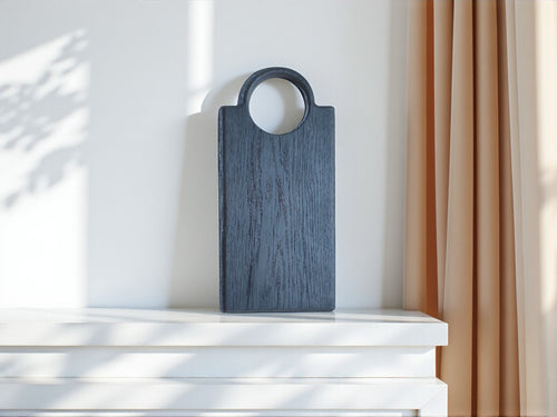 Erleben Sie die Eleganz und Qualität des handgefertigten Oldrye Slim Loop Servierbretts. Dieses Video zeigt das minimalistische Design und die natürliche Maserung des schwarzen Eichenholzes. Weiche Schatten und die Bewegung der Gardinen im Wind unterstreichen die ruhige und luxuriöse Ästhetik, die perfekt in jedes Zuhause passt. Ideal als Schneide- oder Servierbrett für Käse, Wurst oder Brot.